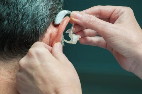 A Doctor Wearing Hearing Aid To His Patient.