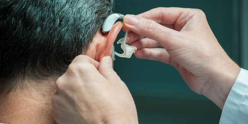 A Doctor Wearing Hearing Aid To His Patient.