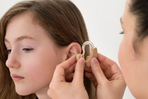 A Doctor Putting Hearing Aid In The Ear of A Girl.