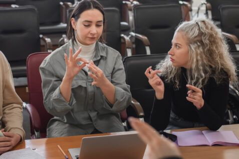 An instructor and trainees communicating in sign language sitting in a training room.