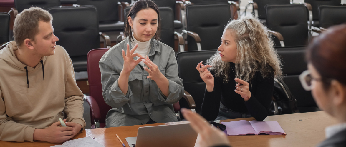 An instructor and trainees communicating in sign language sitting in a training room.